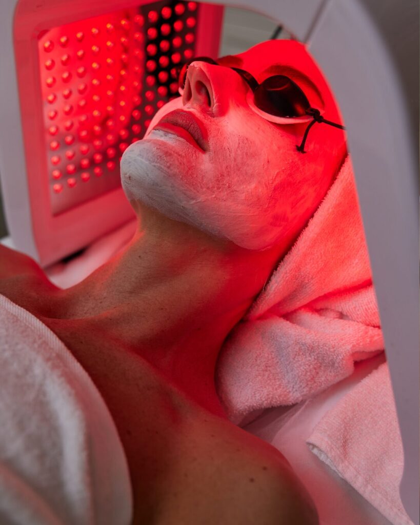 Red Light Therapy in an at-home or spa setting. A woman lies underneath the light, basking in the glow. 